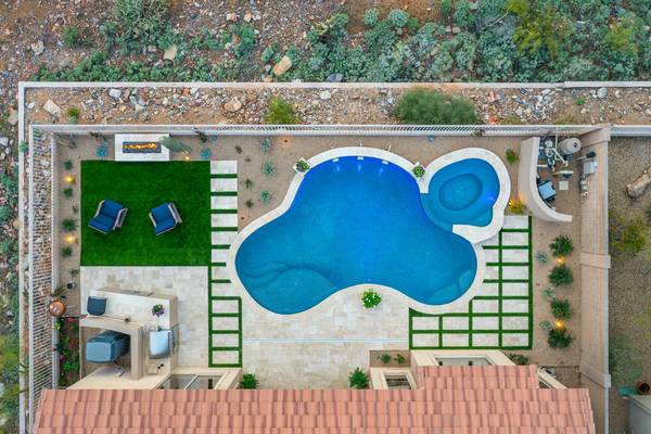 Aerial view of a custom freeform pool with turf, fire pit and paver patio